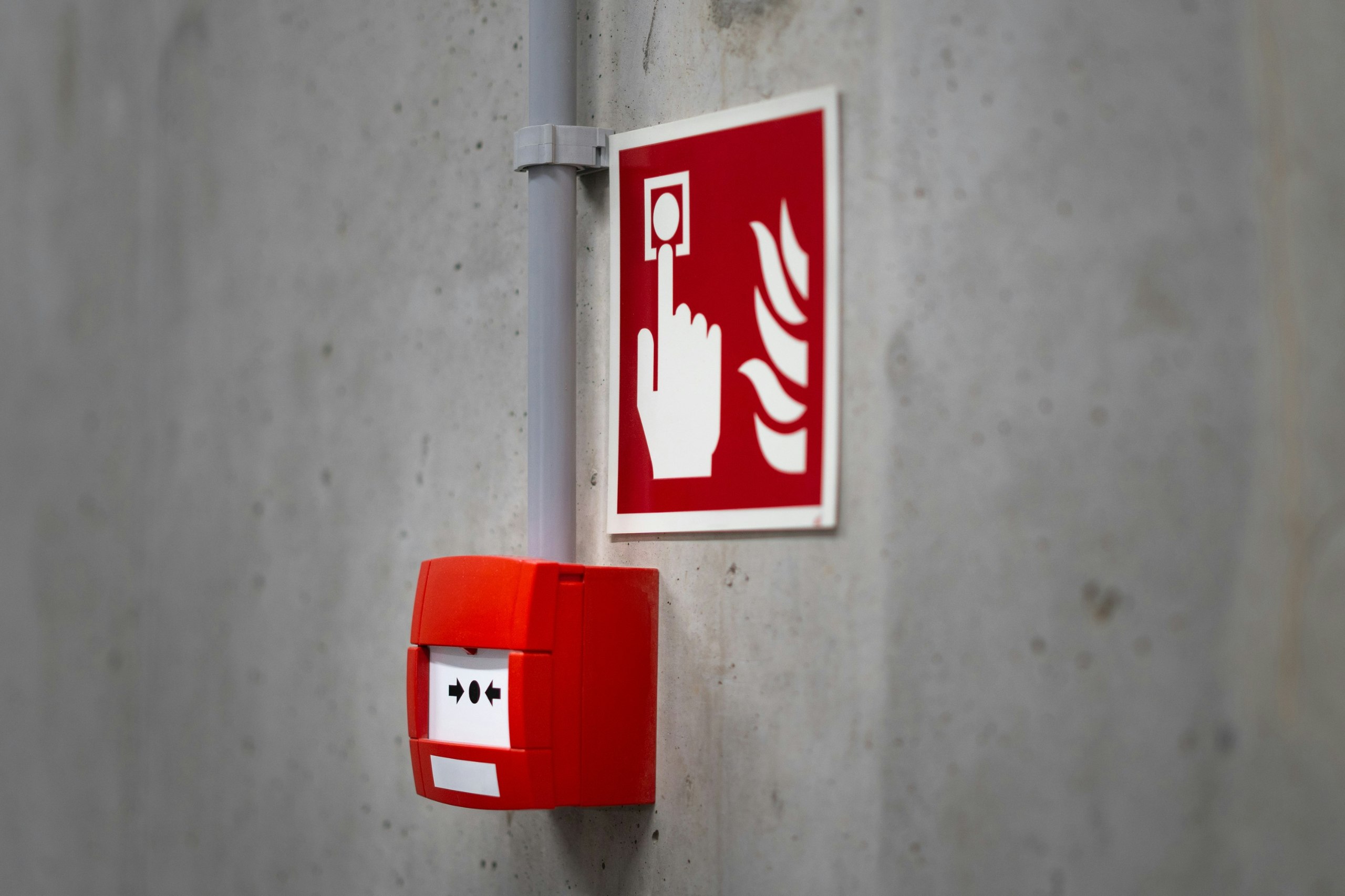 Roter manueller Brandmelder an einer Betonwand